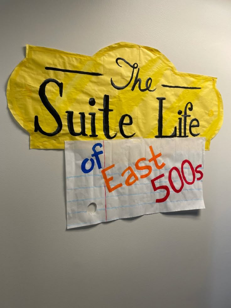 a sign that says the suite life of east 500s hangs on a white wall