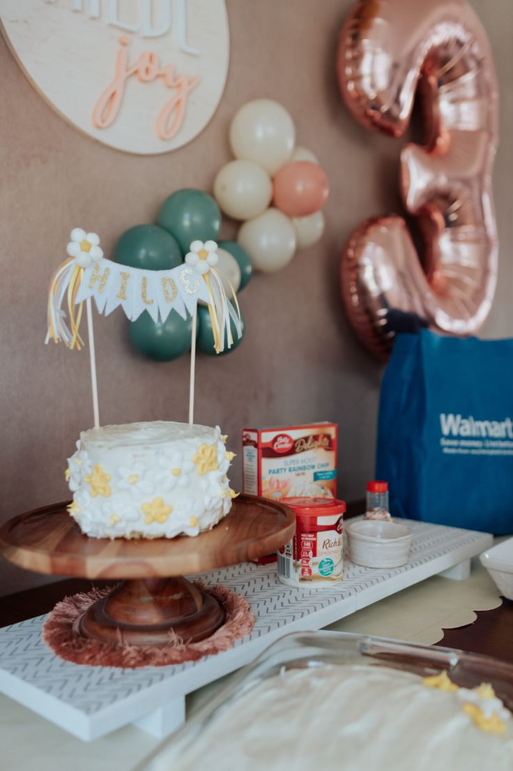 a birthday cake sitting on top of a table next to balloons and confetti