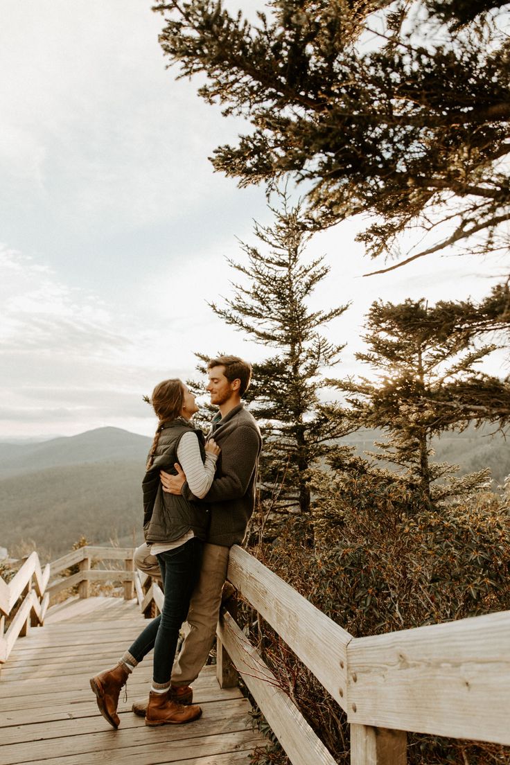 a man and woman standing on a wooden bridge