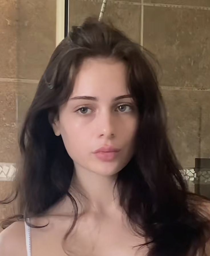 a woman with long hair standing in front of a shower