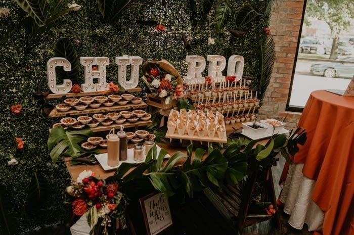 a table filled with food and drinks on top of a wooden table covered in greenery