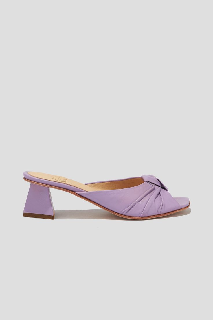 The Greta is a boudoir slipper-inspired mule that captures a playful mix of daytime sensibility & evening refinement. Whether you’re wearing the Greta for daytime play or after-dark doings, you will feel both comfortable and well-turned-out, thanks to a low, triangular heel and a pretty pleated-knot detail at the toe. Style Greta back to loose, casual pants for a breezy date look, or wear them with a cocktail dress to the next wedding on your calendar. Kidskin leather upper, vegetable tanned leather lining, leather outsole. Heel height: 1 ¾ inches (45 mm) Handmade in Argentina Spring Evening Mules With Block Heel, Elegant Almond Toe Slippers For Spring, Elegant Block Heel Mules For Spring, Elegant Spring Mules With Block Heel, Elegant Spring Block Heel Mules, Slip-on Evening Heels For Spring, Chic Summer Slippers With Open Heel, Elegant Pointed Toe Slippers For Spring, Summer Evening Open Toe Slippers