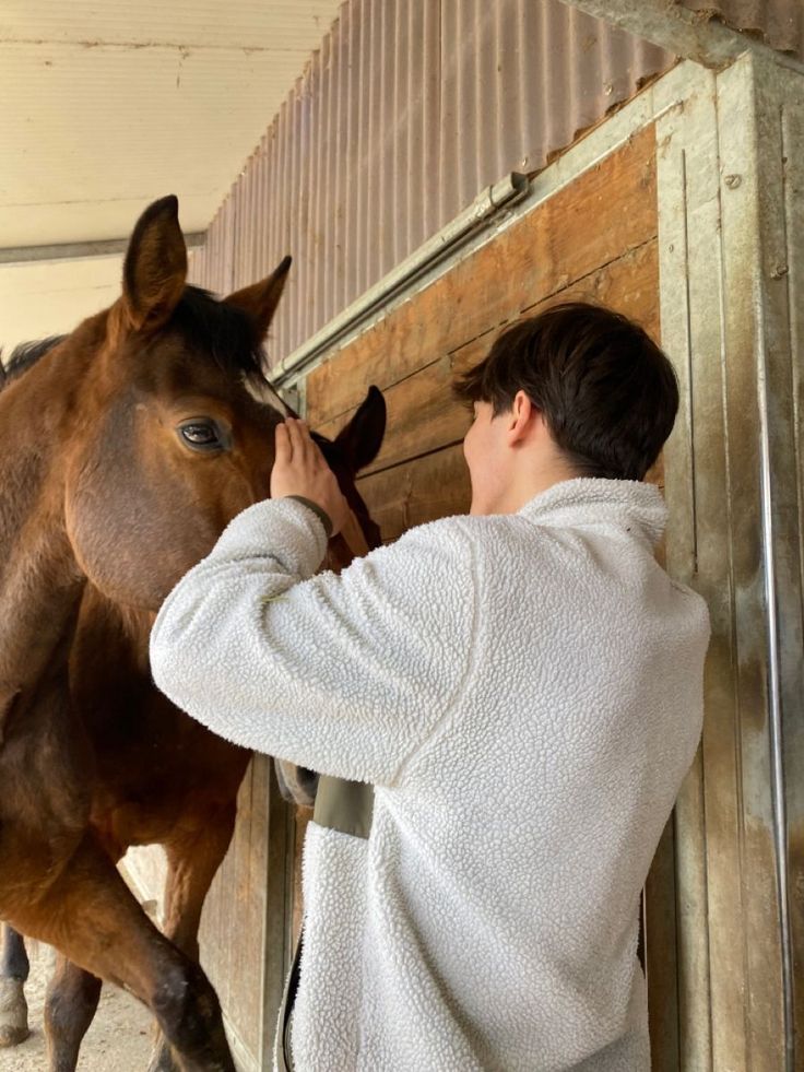 a man is petting the head of a horse