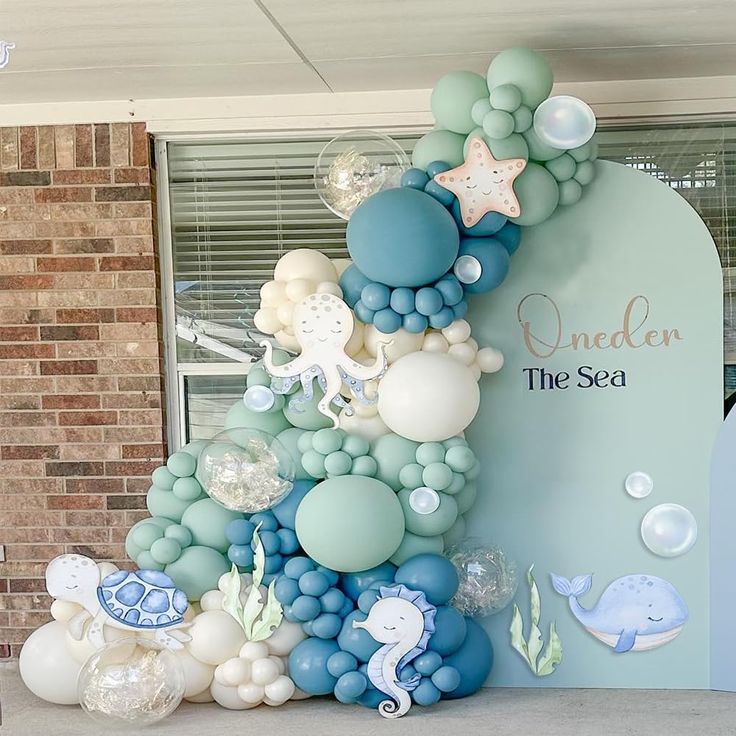 an under the sea themed birthday party with balloons and decorations on display in front of a window