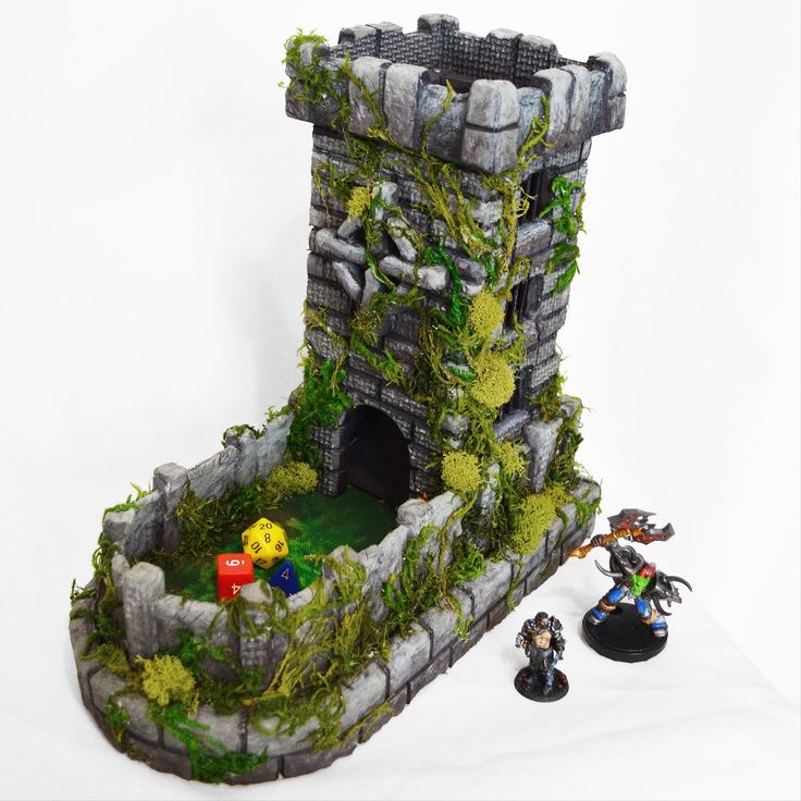 a miniature castle with two figurines in front of it on a white surface