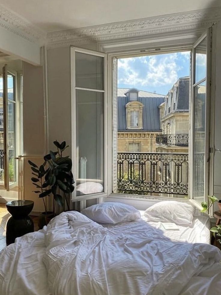 a bed sitting in front of a window next to a potted plant