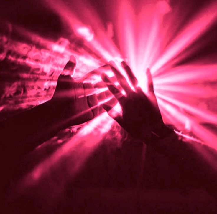 a person holding their hand up in the air with bright light coming from behind them