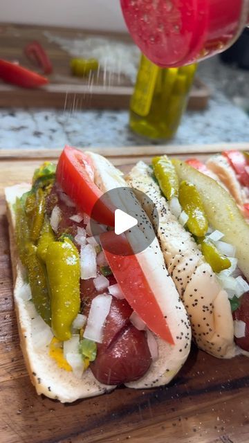 two hot dogs with peppers and onions on a cutting board