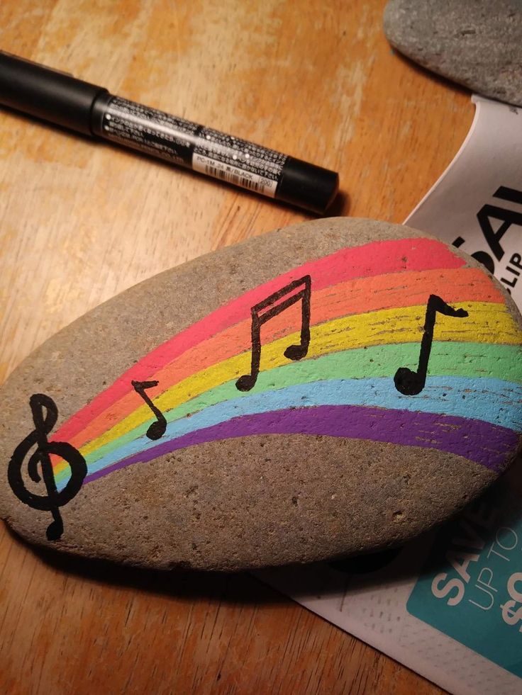 a rock with musical notes painted on it next to a pen and paper clipping