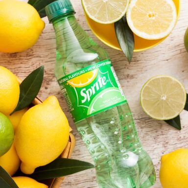 a bottle of sprite water surrounded by lemons and limes