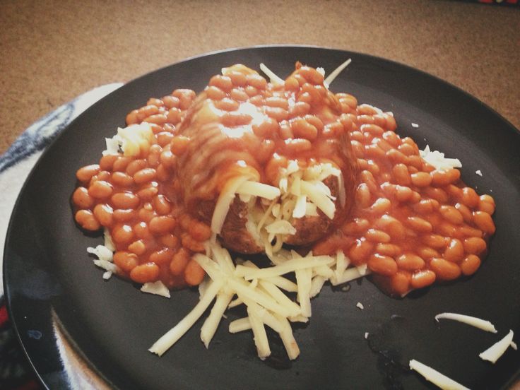 a black plate topped with beans covered in gravy