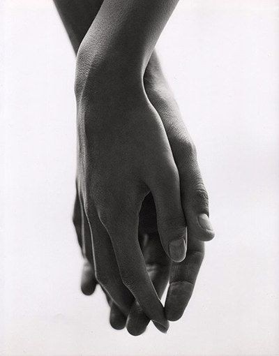 black and white photograph of two hands holding each other's hand, against a white background