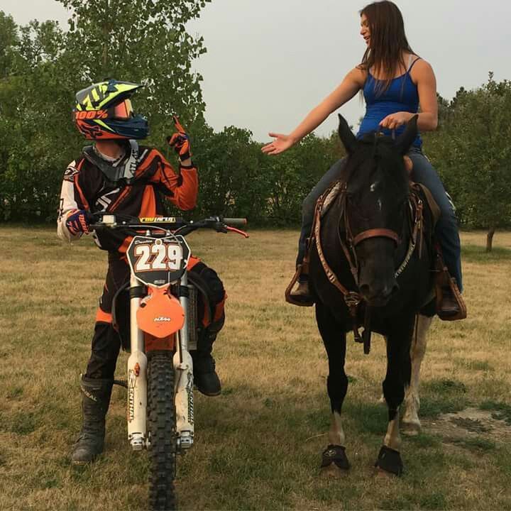 a woman is riding on the back of a brown horse next to a young boy