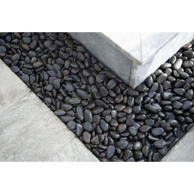 black rocks are laid on the ground next to a cement block