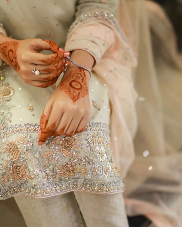 a woman with henna on her hands holding something in one hand and wearing a ring