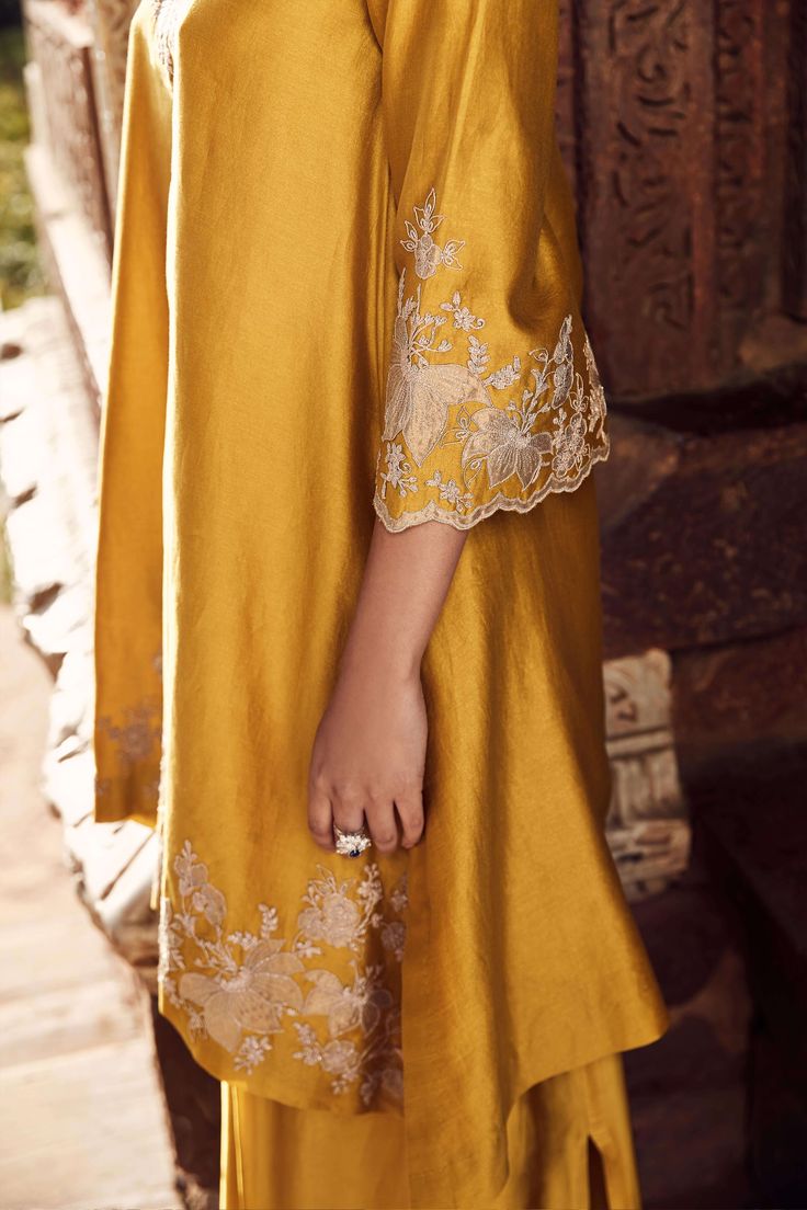 Introducing the sona patti hukum kurta, crafted from the finest mustard linen, a seamless blend of tradition and modernity. This set features intricate floral and paisley appliqué work on a canvas of chanderi, exuding elegance and sophistication. The three-quarter sleeve, v-neck kurta is paired with a voluminous drape skirt, creating a silhouette that captures the essence of the eclectic, empowered modern woman. Whether it's for family functions or ethnic occasions, this two-piece staple is a mu Appliqué Work, Co Ords Outfits, Kurti Style, Kurti Patterns, Pakistani Fashion Casual, Pakistani Fashion Party Wear, Indian Dresses Traditional, Traditional Indian Outfits, Suits Design