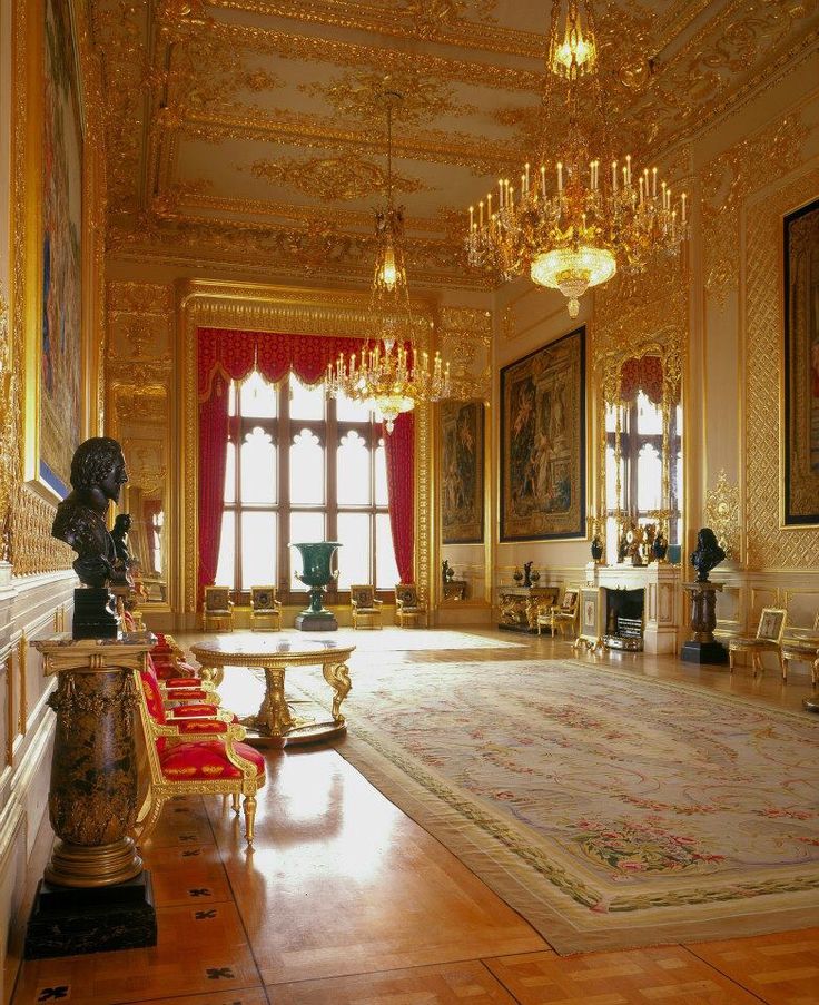 an ornate room with chandeliers and paintings on the walls, carpeted in gold