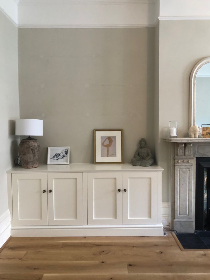 a living room with some white cabinets and pictures on the wall next to a fire place