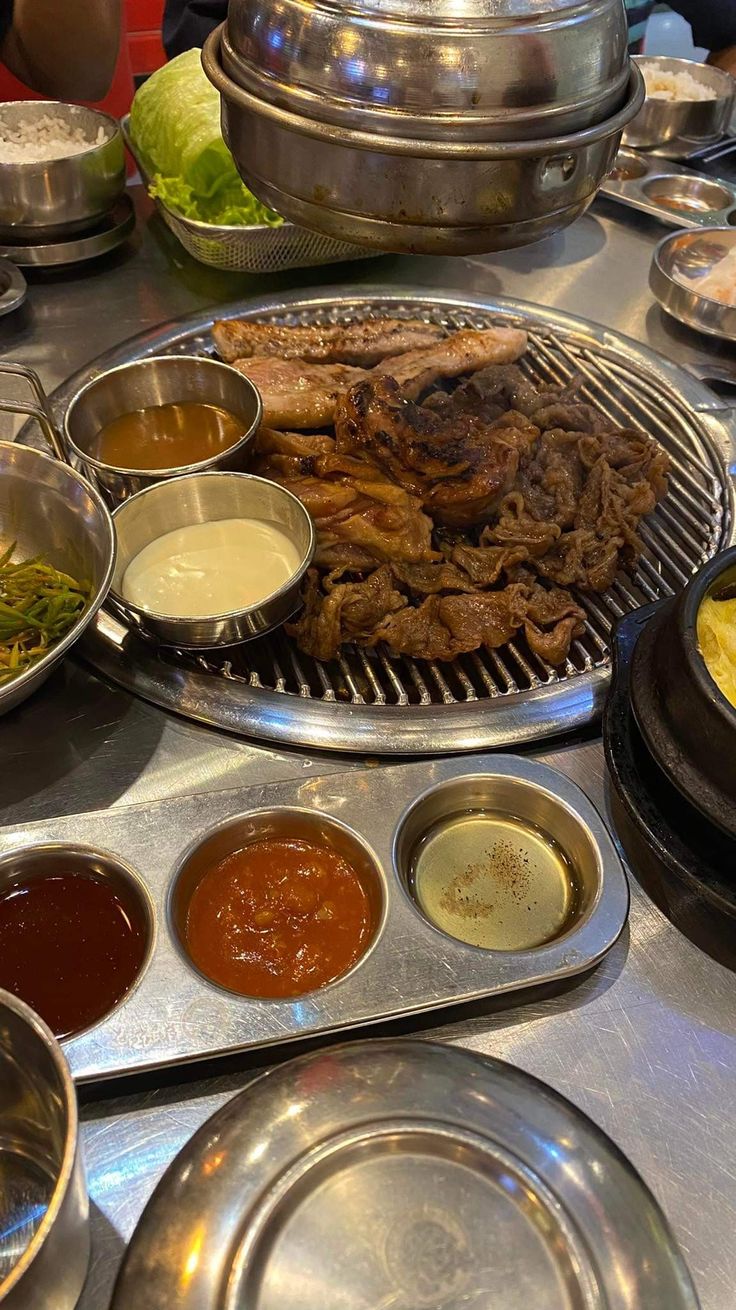 a table topped with lots of different types of food on top of metal pans