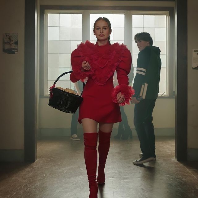 a woman in a red dress is walking down the hall