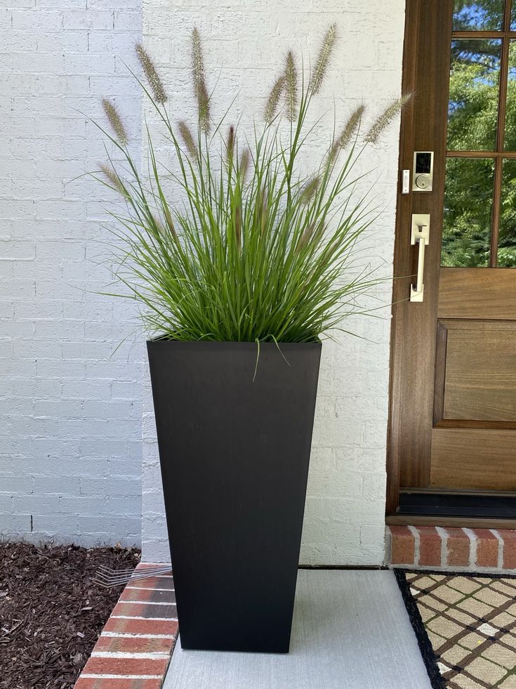 a tall black planter sitting in front of a door