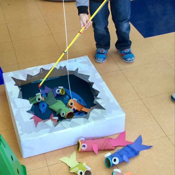 a child is playing with construction paper and scissors in the shape of an origami fish