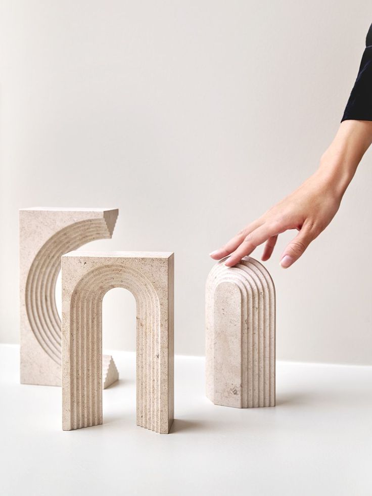 a hand is reaching for the top of two blocks that appear to be made out of marble