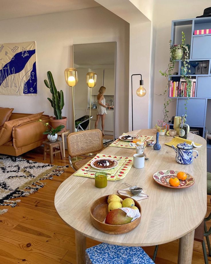 a wooden table topped with plates and bowls filled with fruit next to a couch in a living room