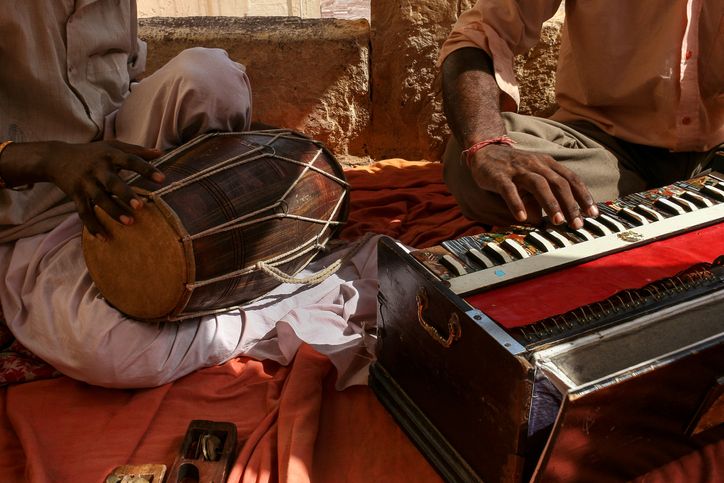 two men sitting on the ground playing musical instruments