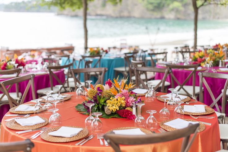 an outdoor dining area with tables and chairs set up for a formal function at the beach