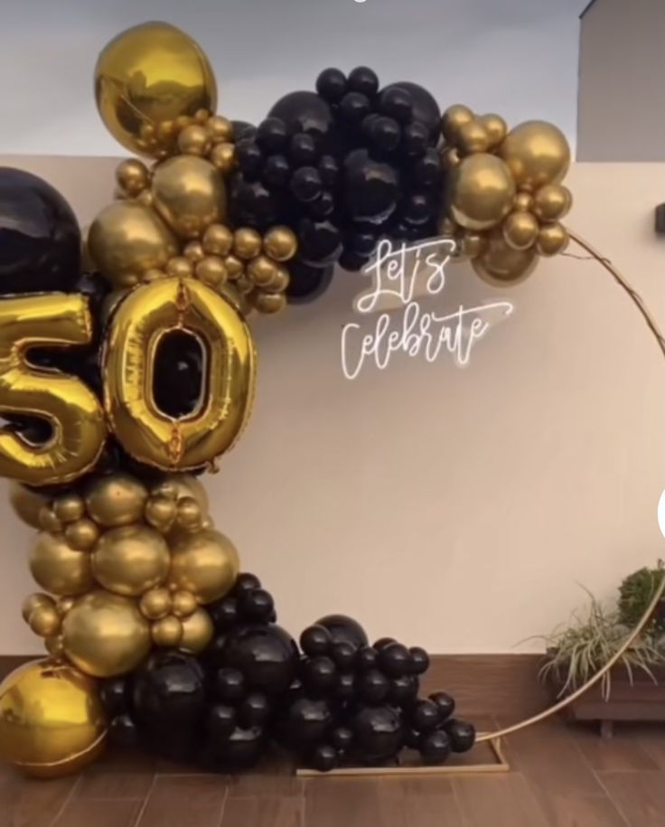 the balloon arch is decorated with black, gold and white balloons that spell 50 years