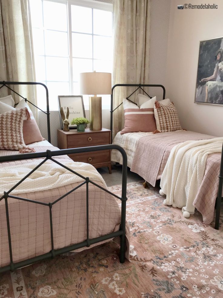 two twin beds in a bedroom with pink bedding and pillows on the floor next to each other