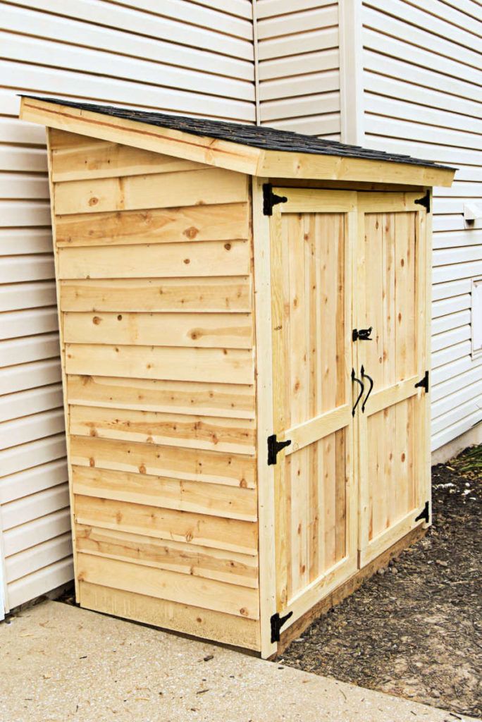 a wooden storage shed sitting in front of a house