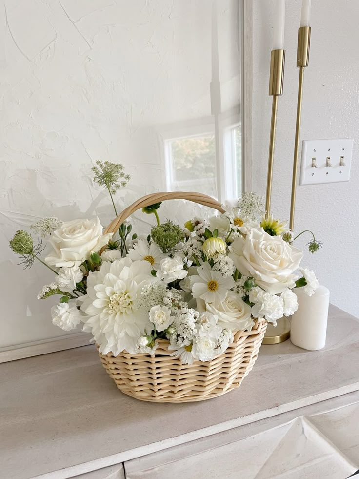 a basket filled with white flowers sitting on top of a dresser