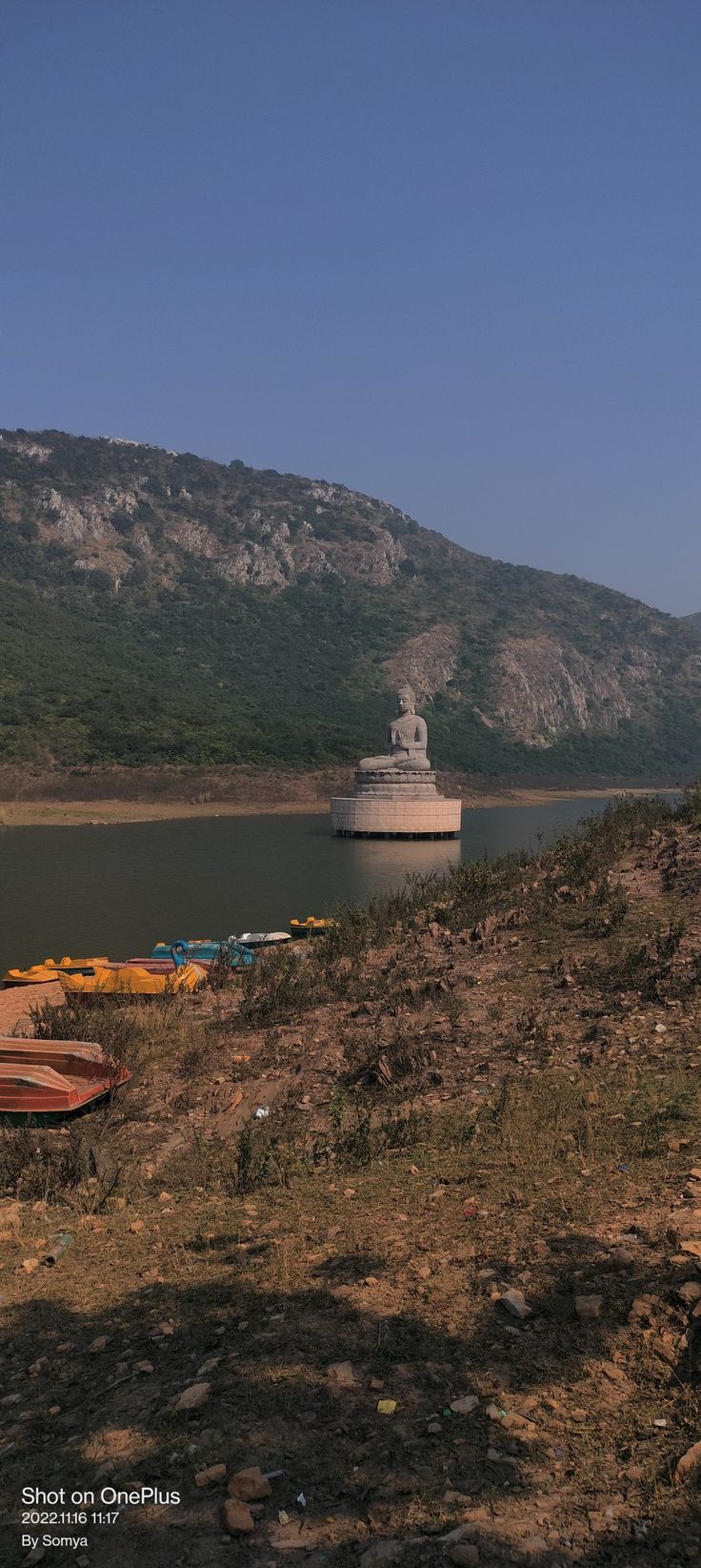 there is a small boat in the water near some hills and boats on the shore