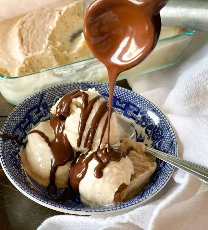 ice cream being drizzled with chocolate sauce on a blue and white plate