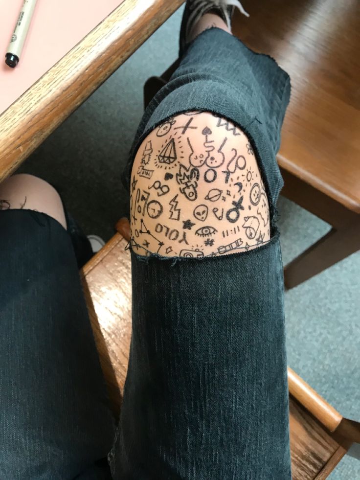 someone with tattoos on their legs sitting at a table