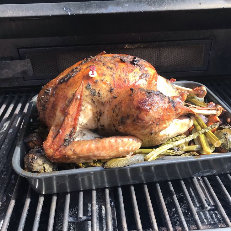 a roasting turkey is on the grill with asparagus