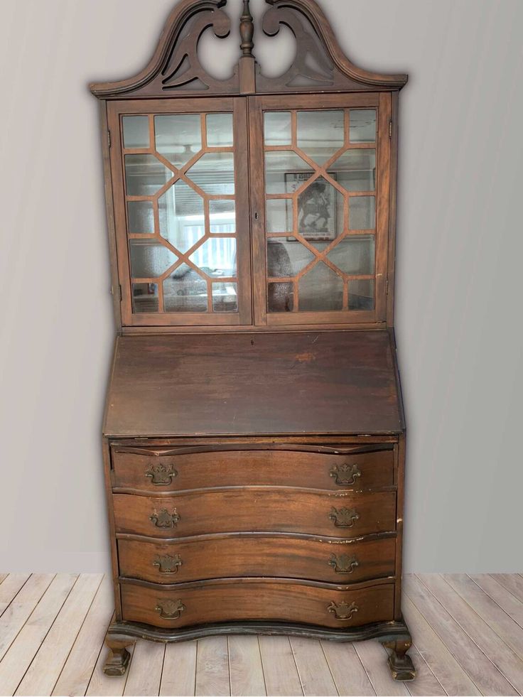 an old wooden desk with glass doors and drawers