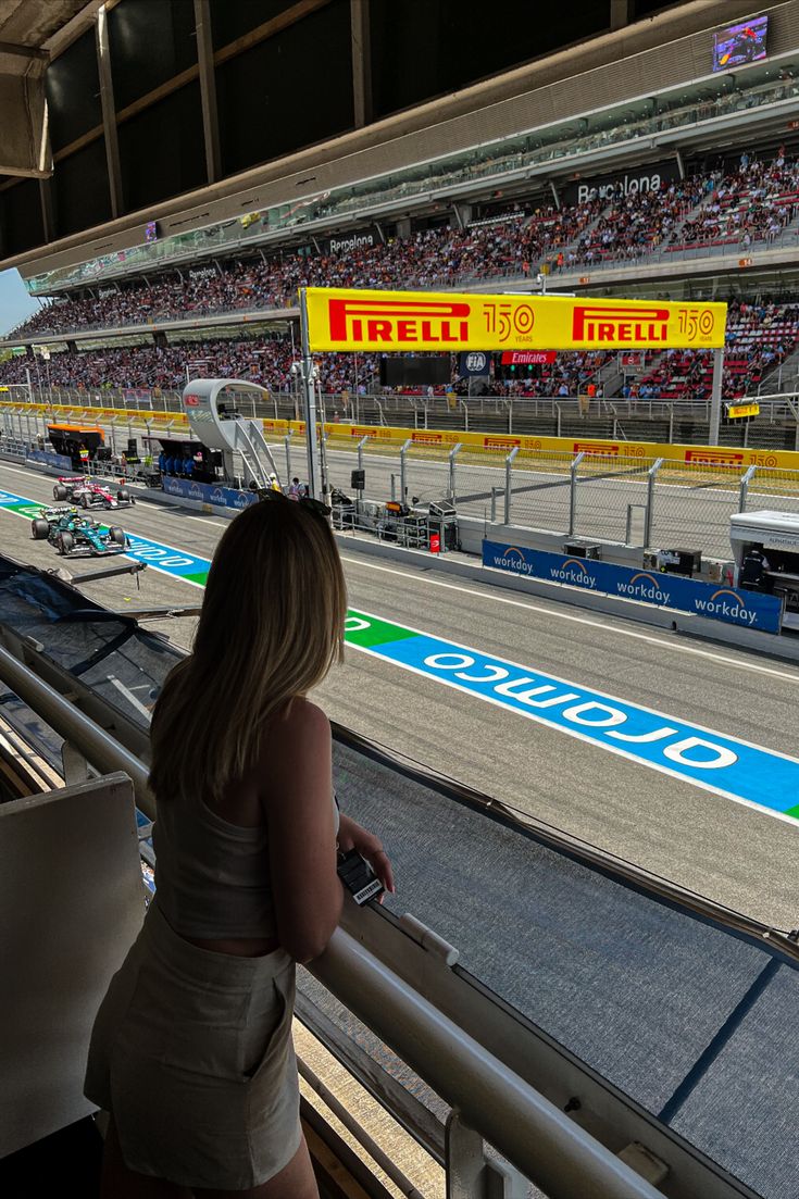 a woman is looking out the window at a race track