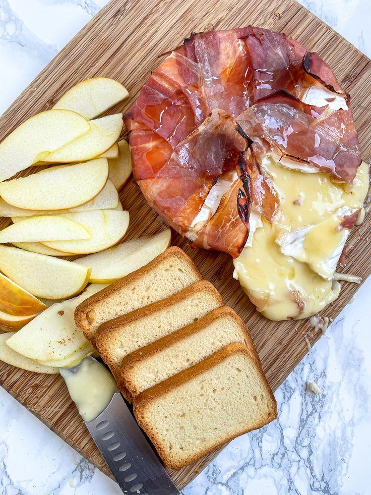 a wooden cutting board topped with slices of bread and sliced apples