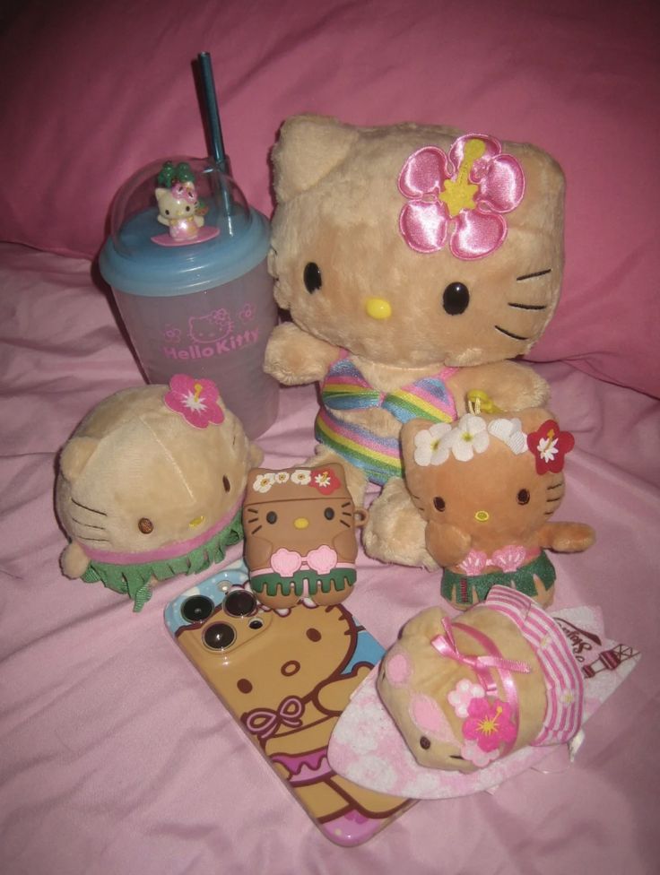 a hello kitty stuffed animal sitting on top of a bed next to two other stuffed animals