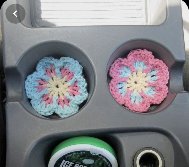 three crocheted flowers are in the center of a cup holder on a vehicle