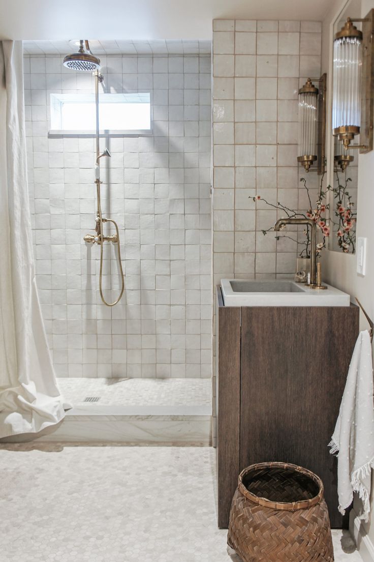 a bathroom with a shower, sink and mirror next to a white rug on the floor