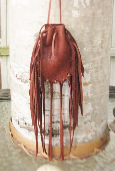 a brown purse hanging from the side of a white pillar with tassels on it