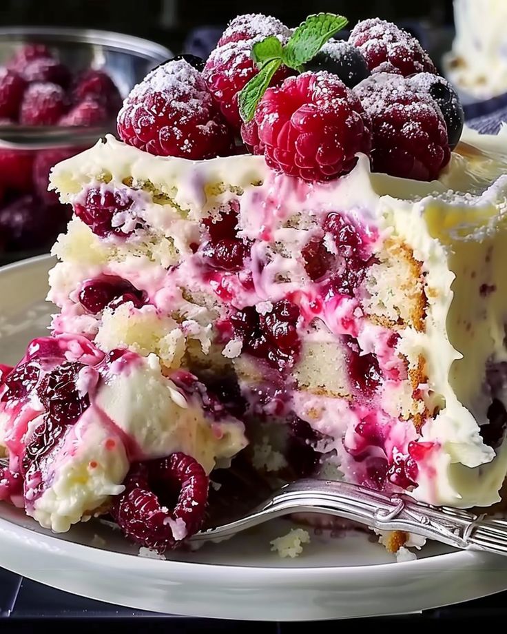 a close up of a piece of cake on a plate with raspberries and powdered sugar