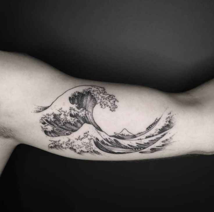 a man's arm with a wave tattoo on it