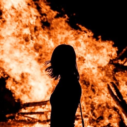 a woman standing in front of a large fire