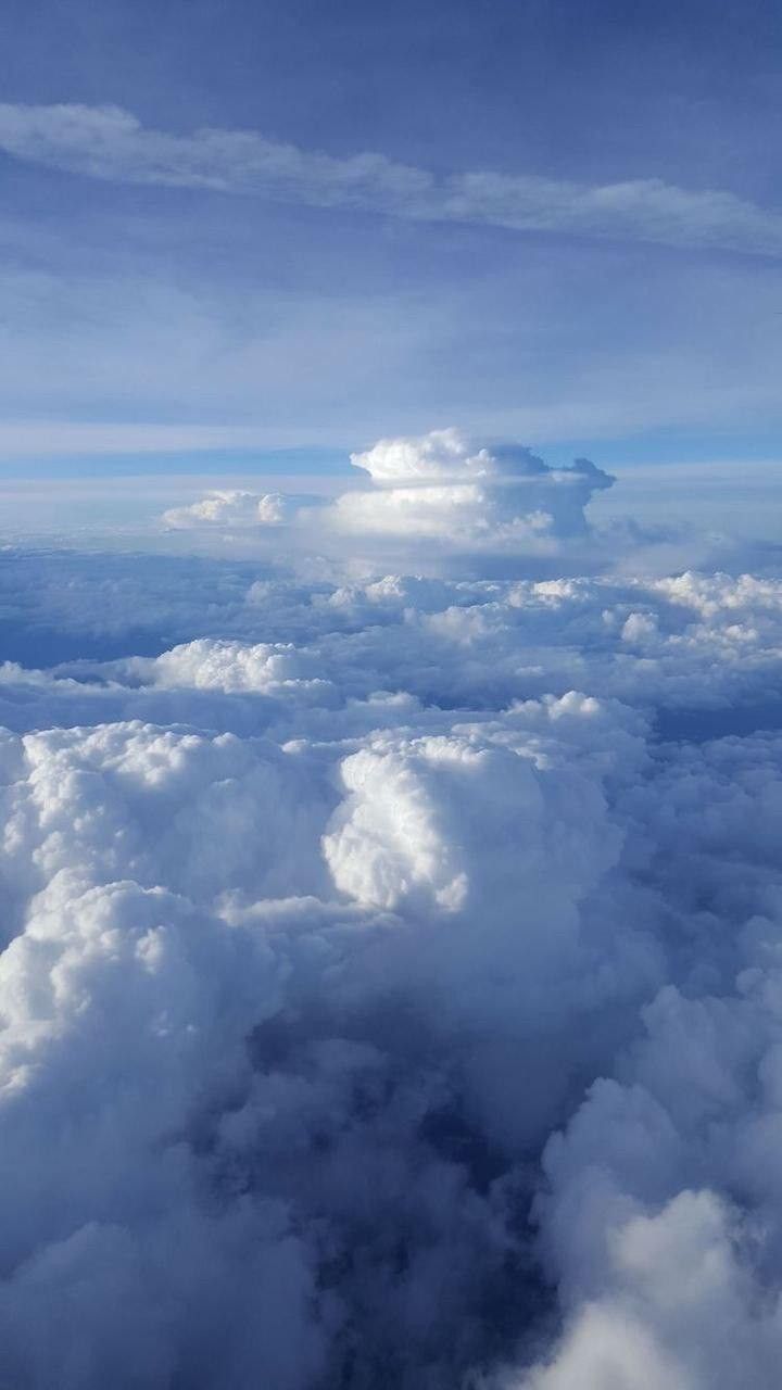 the view from an airplane looking down on clouds and blue sky with white puffy clouds