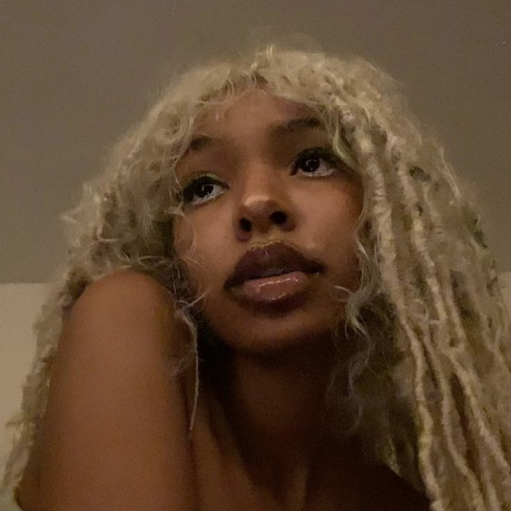 a woman with blonde dreadlocks looking at the camera